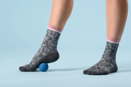 Feet wearing Sockwell socks stepping on a ball